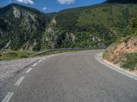 an empty street leads to a mountain valley and a winding, empty road winds through the mountains