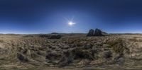 a landscape shot with some large rocks and grass on the ground near a bright blue sky