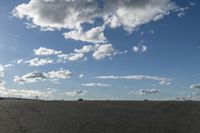 a black car driving in a gravel road next to the ocean on a clear day