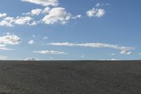 a black car driving in a gravel road next to the ocean on a clear day