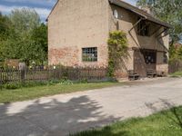 the small brick building has a porch and two benches on the sidewalk in front of it