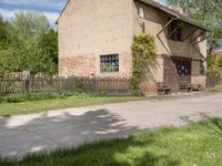 the small brick building has a porch and two benches on the sidewalk in front of it