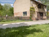 the small brick building has a porch and two benches on the sidewalk in front of it