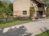 the small brick building has a porch and two benches on the sidewalk in front of it