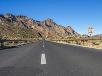 the desert road and mountains are empty of cars and a sign points out where to go