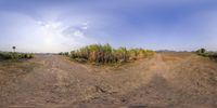 a wide angle view of a dirt road and a field with some grass in the middle