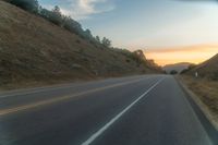 a photo of a country road with sun setting behind it from the back seat of a car