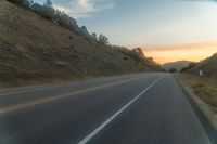 a photo of a country road with sun setting behind it from the back seat of a car