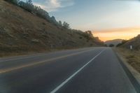 a photo of a country road with sun setting behind it from the back seat of a car