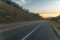 a photo of a country road with sun setting behind it from the back seat of a car