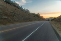 a photo of a country road with sun setting behind it from the back seat of a car