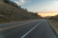 a photo of a country road with sun setting behind it from the back seat of a car