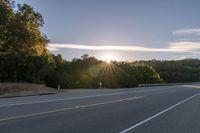 the sun is setting in the distance behind trees on the highway that goes from sunset to sunset