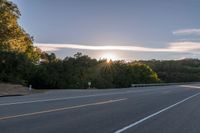 the sun is setting in the distance behind trees on the highway that goes from sunset to sunset