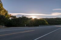 the sun is setting in the distance behind trees on the highway that goes from sunset to sunset