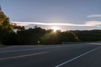 the sun is setting in the distance behind trees on the highway that goes from sunset to sunset