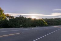 the sun is setting in the distance behind trees on the highway that goes from sunset to sunset