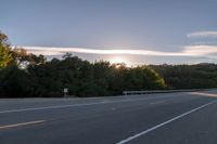 the sun is setting in the distance behind trees on the highway that goes from sunset to sunset