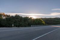 the sun is setting in the distance behind trees on the highway that goes from sunset to sunset