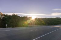 the sun is setting in the distance behind trees on the highway that goes from sunset to sunset