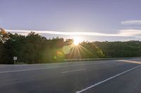 the sun is setting in the distance behind trees on the highway that goes from sunset to sunset