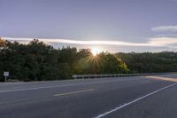 the sun is setting in the distance behind trees on the highway that goes from sunset to sunset