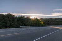 the sun is setting in the distance behind trees on the highway that goes from sunset to sunset