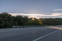 the sun is setting in the distance behind trees on the highway that goes from sunset to sunset