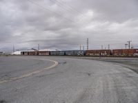 an empty parking lot with tracks and freight train cars on it while there is no one on the tracks