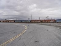 an empty parking lot with tracks and freight train cars on it while there is no one on the tracks