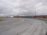 an empty parking lot with tracks and freight train cars on it while there is no one on the tracks