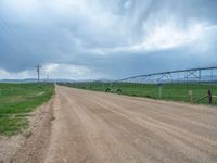 an image of a dirt road with power lines above it in the background of a field