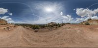 the view into the sky over a dirt road with dirt and trees around it and a blue sky overhead