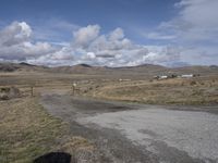 there is a grassy field with hills in the background and an empty road on the ground