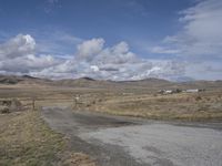 there is a grassy field with hills in the background and an empty road on the ground