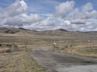 there is a grassy field with hills in the background and an empty road on the ground