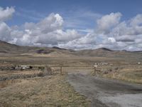 there is a grassy field with hills in the background and an empty road on the ground