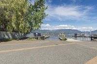 a street with a boat dock and a house next to it and water in the background