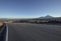 an open road stretching into the distance on a clear day with mountains and a blue sky in the distance