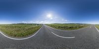 three point perspective view of a road near a grassy field and mountains with a few clouds