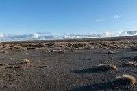 a lone rock formation in a deserted, barren area on a sunny day with blue sky