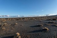 a lone rock formation in a deserted, barren area on a sunny day with blue sky