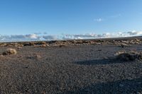 a lone rock formation in a deserted, barren area on a sunny day with blue sky