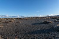 a lone rock formation in a deserted, barren area on a sunny day with blue sky