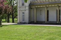 a tall white building with pillars and windows on the second floor has a lawn with a dog laying in front of it