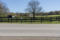 a horse is in the pasture by the road and fenced off by a bench