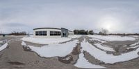 snow on the ground near an office building with many windows in a rural area surrounded by mountains and trees