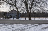 a barn is sitting behind some bare trees on a wintery day - like scene