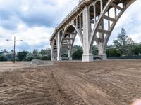 there is an image of a person looking at the ground in the dirt with a bridge above them