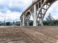 there is an image of a person looking at the ground in the dirt with a bridge above them